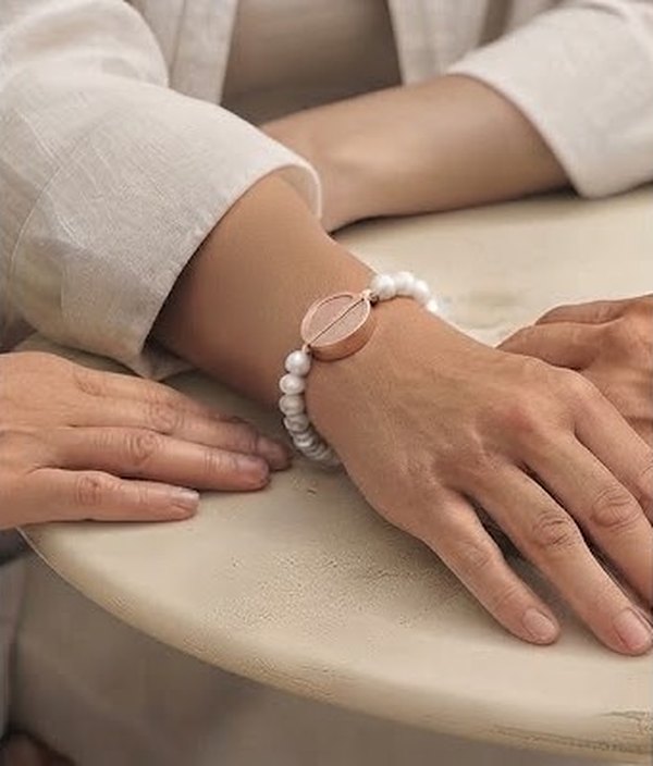 A wrist in a cream linen sleeve wearing The Beaded: freshwater pearls with the Juni Charm